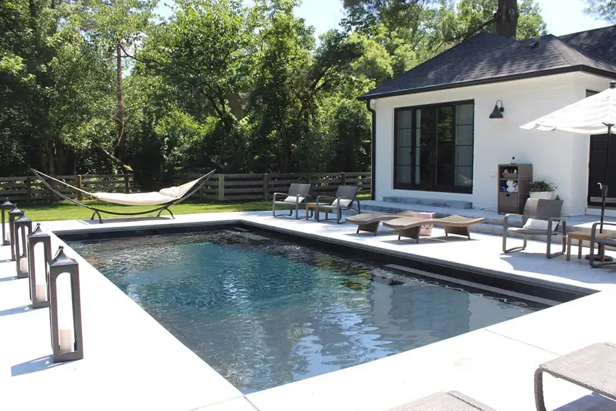 dark lined in-ground swimming pool surrounded by seating options, including a free-standing hammock - Decatur, IL
